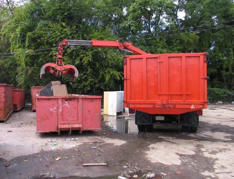 Crew loading materials into a skip with safety gear visible